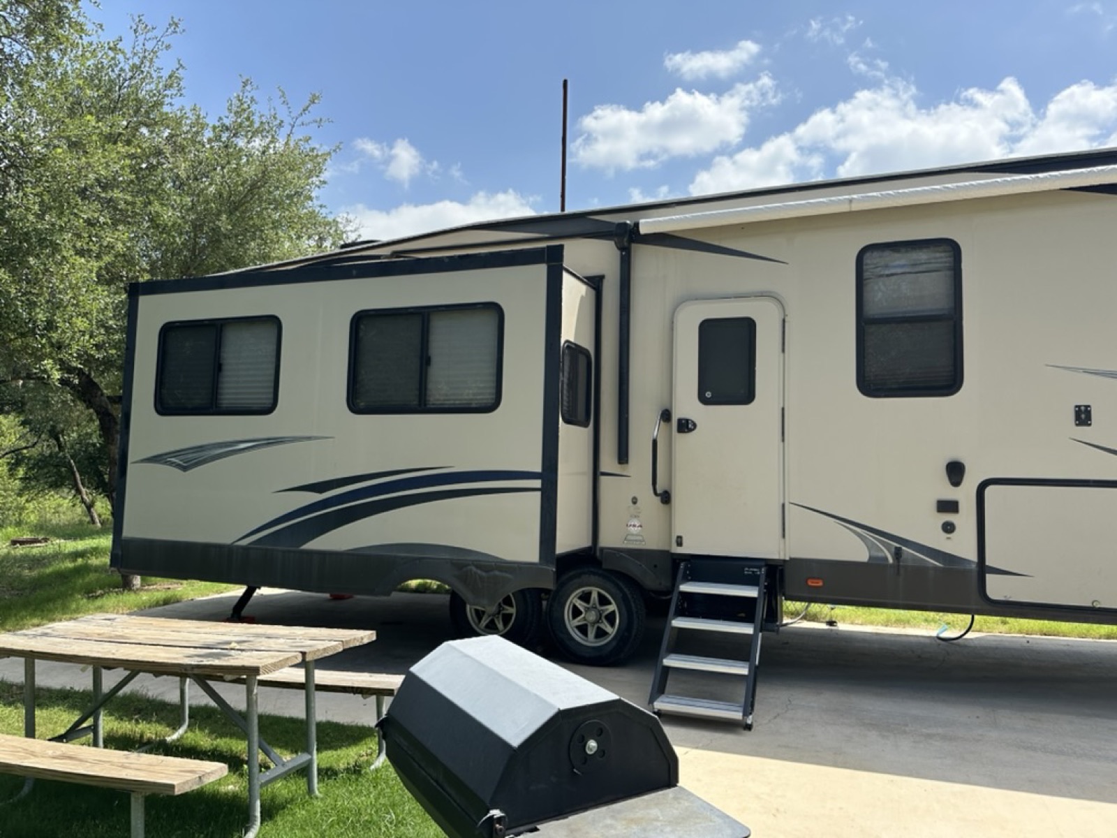 Side profile of the Hemisphere Lite fifth wheel with entry steps and campsite picnic table